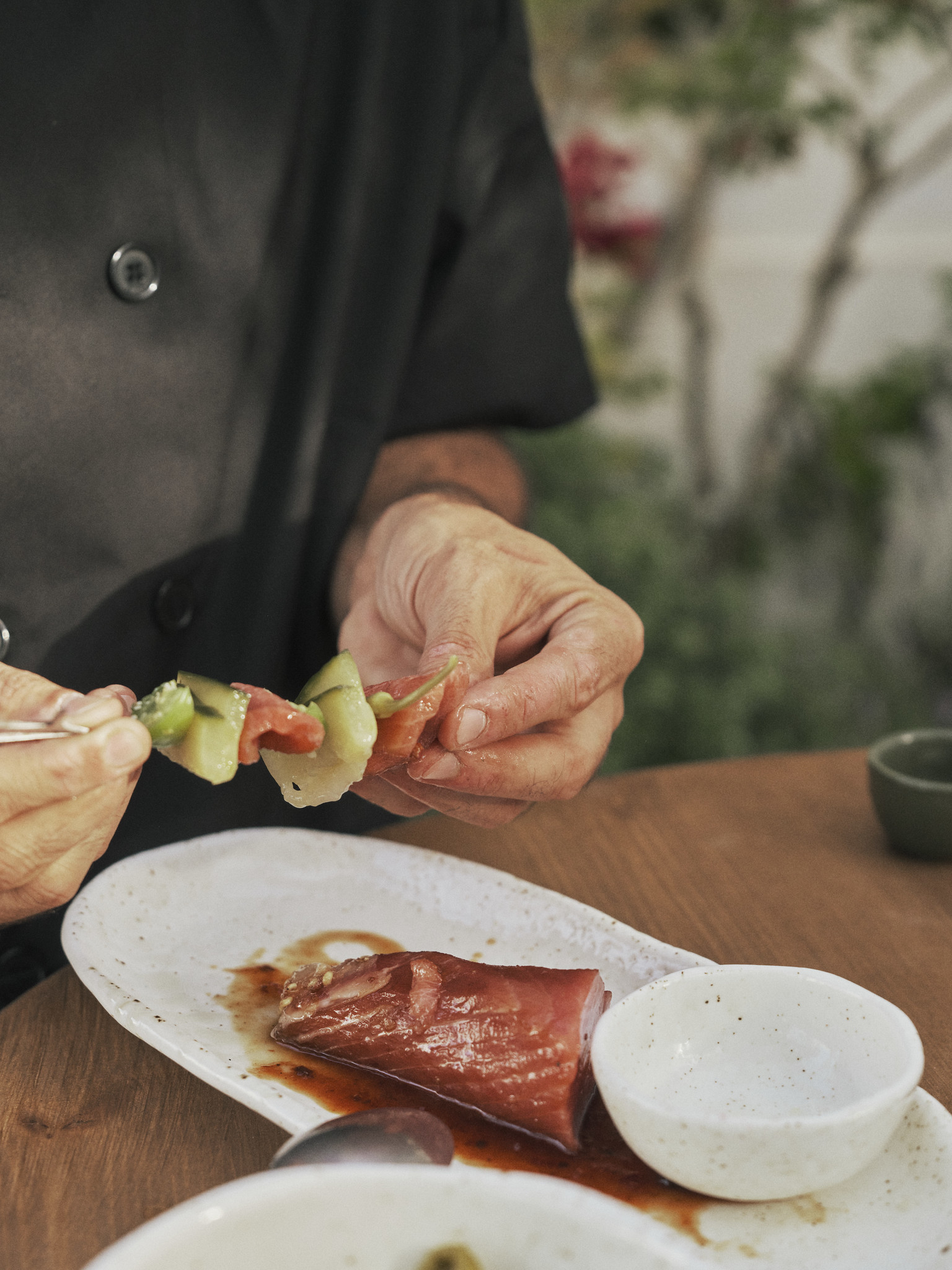 A chef preparing a tuna skewer at the pass